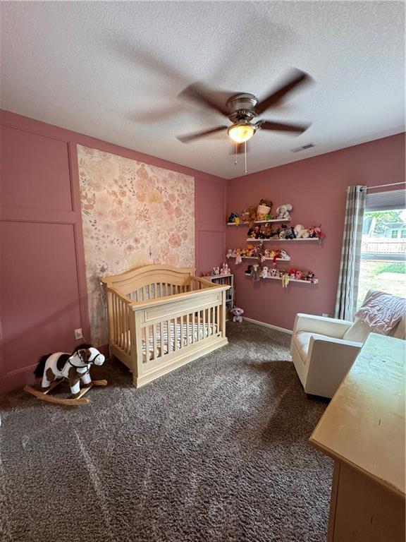 1141 S Main St, Ottawa, KS 66067 - carpeted bedroom with a textured ceiling, ceiling fan, and a crib