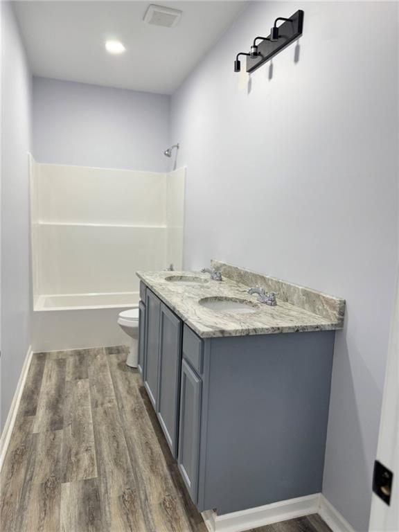 213 Bald Eagle Dr, La Cygne, KS 66040 - full bathroom with wood finished floors, double vanity, and shower / tub combination