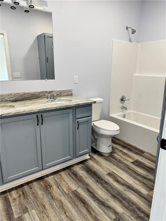 213 Bald Eagle Dr, La Cygne, KS 66040 - full bathroom featuring double vanity, shower / washtub combination, and wood finished floors