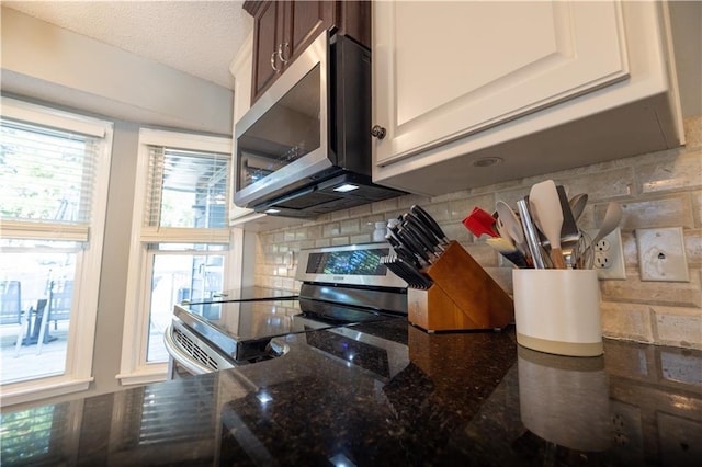 1604 SW 21st St, Blue Springs, MO 64015 - kitchen view of appliances with stainless steel finishes, backsplash, dark stone counters, and a textured ceiling