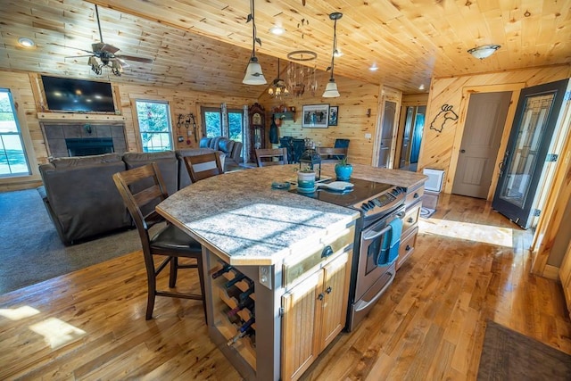 28909 E 297th St, Garden City, MO 64747 - kitchen with stainless steel range with electric stovetop, wood walls, wood ceiling, ceiling fan, and a kitchen bar