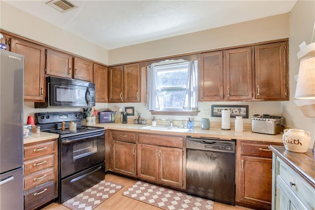 9514 W 77th Ter, Overland Park, KS 66204 - kitchen featuring black appliances, light countertops, brown cabinetry, and light wood-type flooring