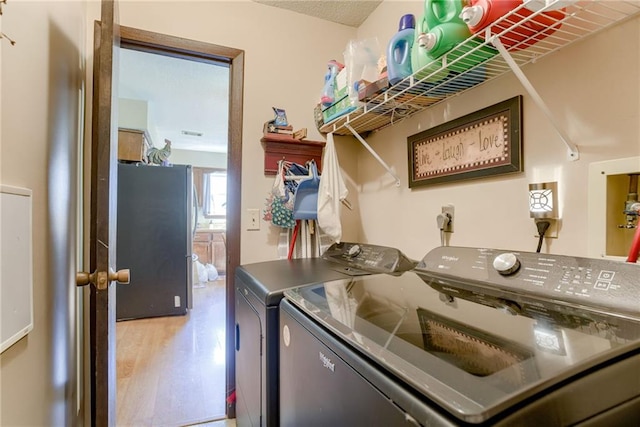 9514 W 77th Ter, Overland Park, KS 66204 - kitchen featuring washing machine and dryer, light wood-style flooring, and freestanding refrigerator