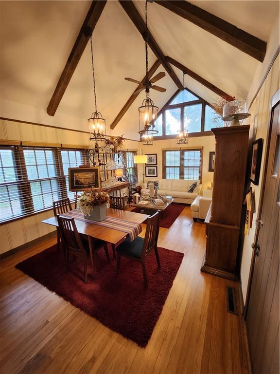 315 N 1st St, Independence, KS 67301 - dining area featuring a chandelier, beamed ceiling, high vaulted ceiling, wood finished floors, and a ceiling fan