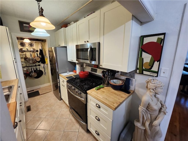 315 N 1st St, Independence, KS 67301 - kitchen featuring appliances with stainless steel finishes, wooden counters, white cabinets, light tile patterned flooring, and pendant lighting