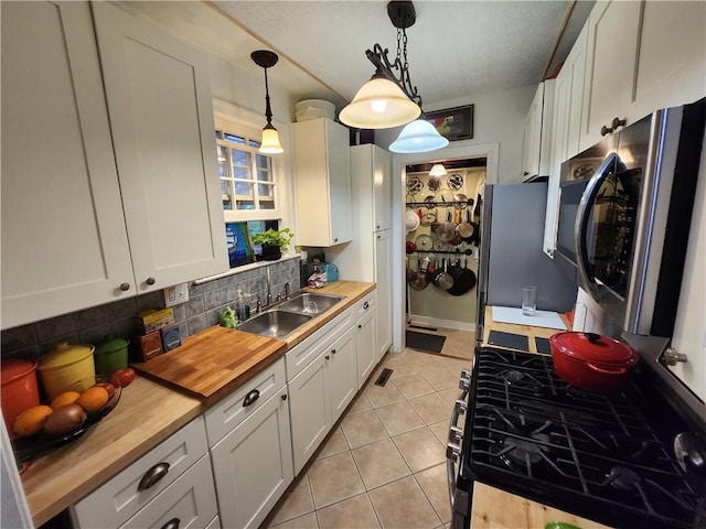 315 N 1st St, Independence, KS 67301 - kitchen with butcher block counters, stainless steel appliances, decorative backsplash, white cabinets, and light tile patterned floors