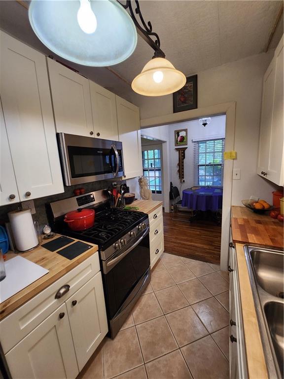 315 N 1st St, Independence, KS 67301 - kitchen featuring butcher block counters, appliances with stainless steel finishes, white cabinets, and light tile patterned flooring