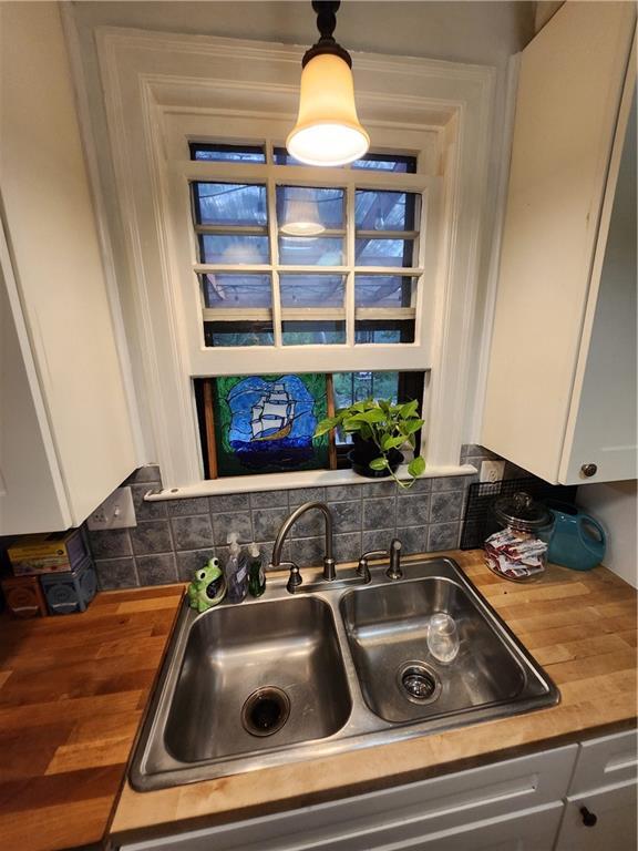 315 N 1st St, Independence, KS 67301 - kitchen with butcher block countertops, white cabinetry, and tasteful backsplash