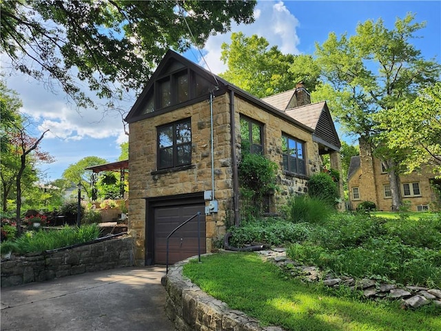 315 N 1st St, Independence, KS 67301 - view of property exterior featuring concrete driveway, an attached garage, stone siding, a chimney, and roof with shingles