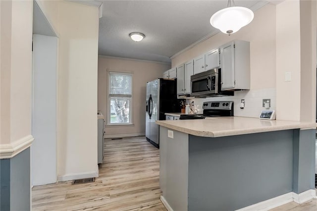 404 S Sycamore St, Ottawa, KS 66067 - kitchen featuring stainless steel appliances, light countertops, ornamental molding, light wood finished floors, and a peninsula