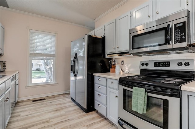 404 S Sycamore St, Ottawa, KS 66067 - kitchen featuring appliances with stainless steel finishes, crown molding, light countertops, healthy amount of natural light, and light wood-style floors
