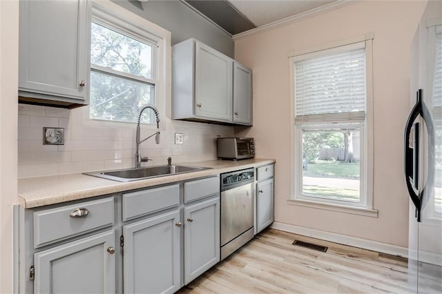 404 S Sycamore St, Ottawa, KS 66067 - kitchen with stainless steel dishwasher, crown molding, decorative backsplash, healthy amount of natural light, and light wood-type flooring