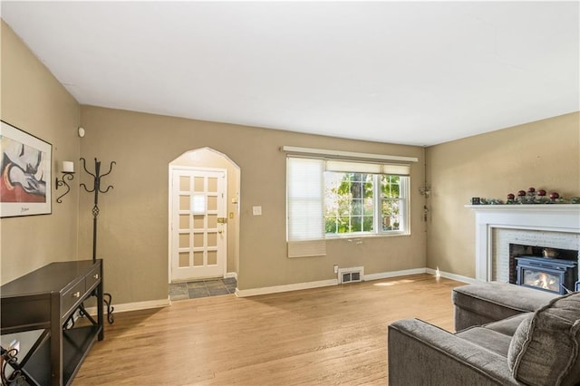 711 E 72nd Ter, Kansas City, MO 64131 - living area featuring wood finished floors, a warm lit fireplace, and arched walkways