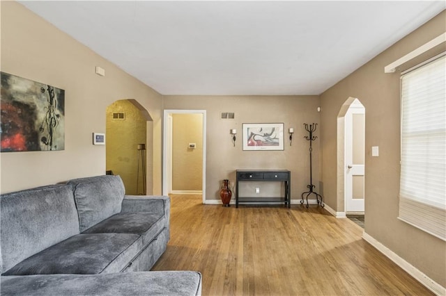 711 E 72nd Ter, Kansas City, MO 64131 - living area with arched walkways, wood finished floors, and plenty of natural light