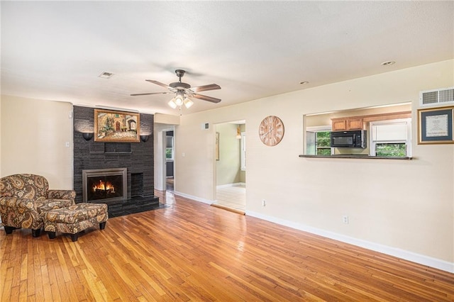 6327 Yecker Ave, Kansas City, KS 66104 - living room featuring light wood-style flooring, a fireplace, and a ceiling fan