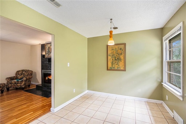 6327 Yecker Ave, Kansas City, KS 66104 - unfurnished room with a fireplace, a textured ceiling, and light wood finished floors