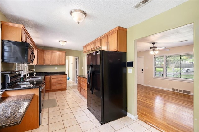 6327 Yecker Ave, Kansas City, KS 66104 - kitchen featuring black appliances, light tile patterned flooring, a ceiling fan, dark stone countertops, and a textured ceiling