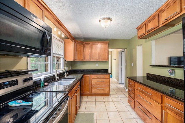 6327 Yecker Ave, Kansas City, KS 66104 - kitchen with black appliances, light tile patterned flooring, brown cabinets, a textured ceiling, and dark stone counters
