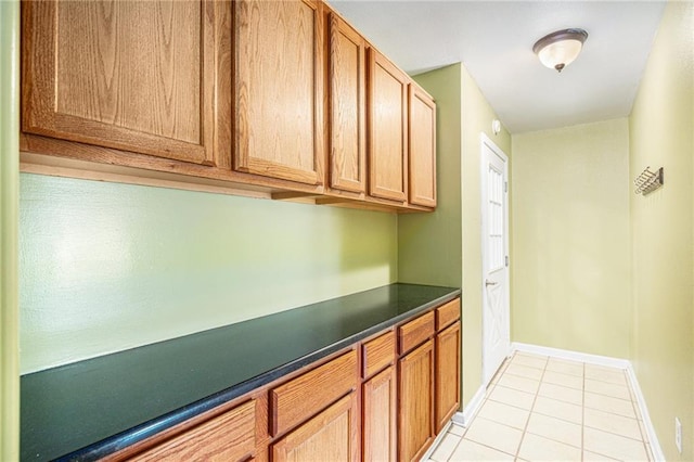 6327 Yecker Ave, Kansas City, KS 66104 - kitchen with dark countertops, light tile patterned floors, and brown cabinetry