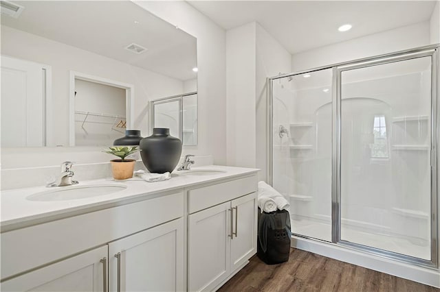 21807 Lucca Ln, Peculiar, MO 64078 - bathroom featuring a shower stall, wood finished floors, double vanity, a spacious closet, and recessed lighting