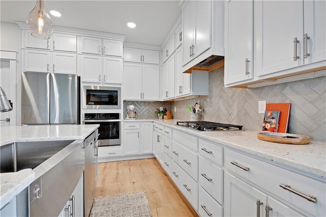 24704 W 76th St, Shawnee, KS 66227 - kitchen featuring stainless steel appliances, white cabinets, decorative backsplash, light wood-style floors, and light stone countertops
