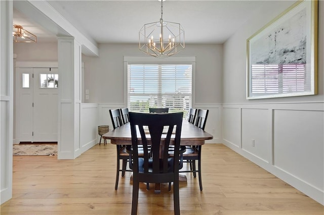 24704 W 76th St, Shawnee, KS 66227 - dining room with a chandelier, a decorative wall, light wood-style floors, and wainscoting