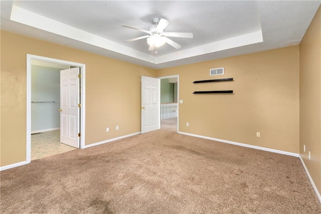 4204 Broadway Ter, Leavenworth, KS 66048 - unfurnished bedroom featuring a tray ceiling, carpet flooring, a walk in closet, a ceiling fan, and a textured ceiling