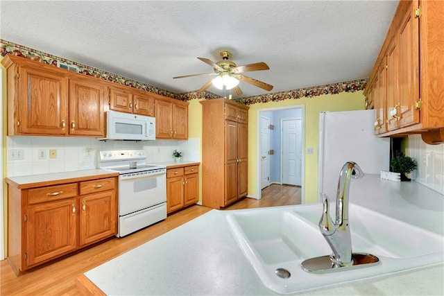 4204 Broadway Ter, Leavenworth, KS 66048 - kitchen featuring white appliances, light wood-type flooring, ceiling fan, backsplash, and light countertops