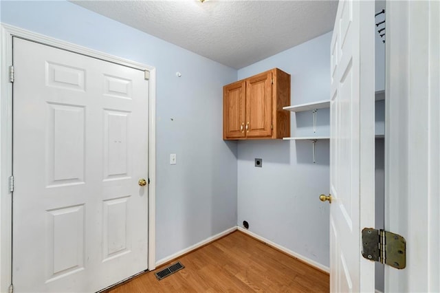 4204 Broadway Ter, Leavenworth, KS 66048 - laundry area with electric dryer hookup, cabinet space, light wood-type flooring, and a textured ceiling