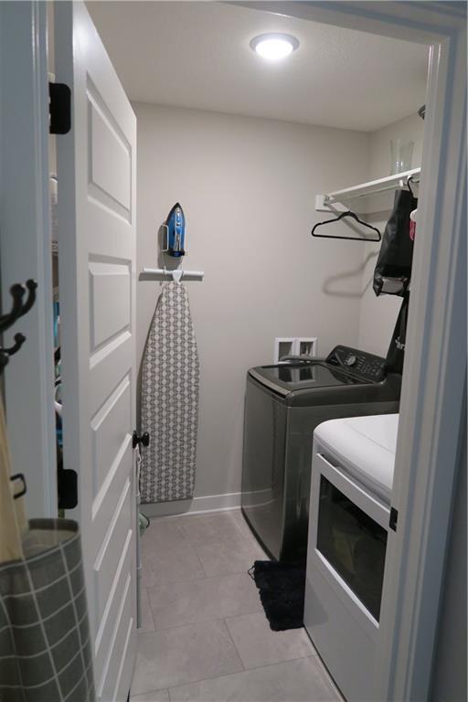 SW 8th St Unit 8819, Blue Springs, MO 64064 - washroom with washer and clothes dryer, light tile patterned floors, and recessed lighting