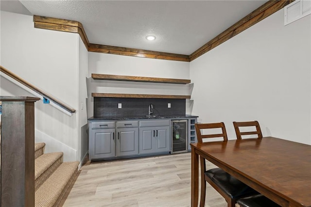 227 SW Eagles Ridge Dr, Blue Springs, MO 64014 - indoor wet bar with decorative backsplash, beverage cooler, light wood-type flooring, stairway, and recessed lighting