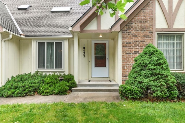 10432 Bond St, Overland Park, KS 66214 - view of exterior entry with board and batten siding, brick siding, and roof with shingles