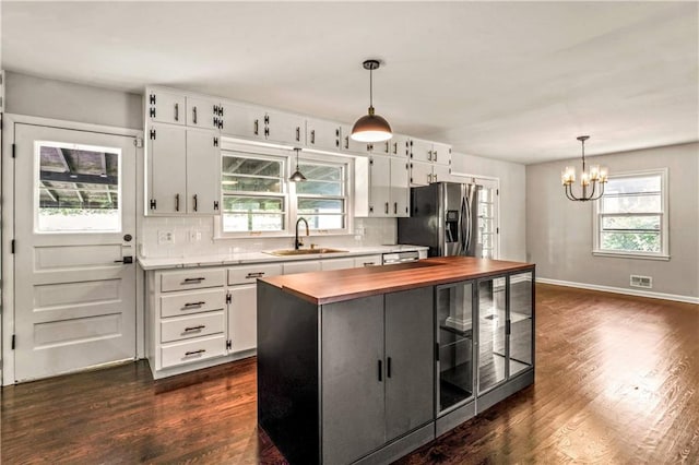 1480 E 76th Ter, Kansas City, MO 64131 - kitchen with butcher block counters, stainless steel refrigerator with ice dispenser, a chandelier, dark wood-style floors, and healthy amount of natural light
