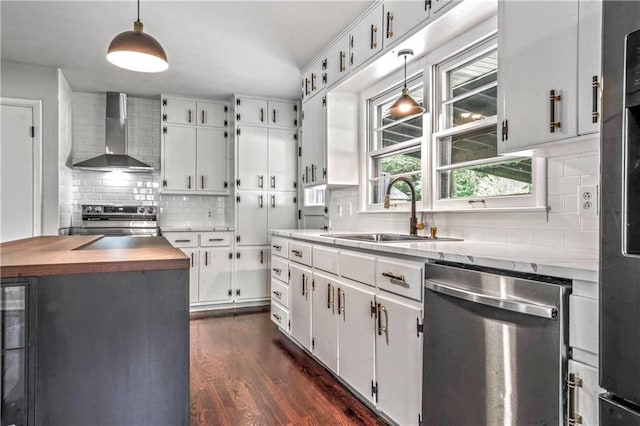 1480 E 76th Ter, Kansas City, MO 64131 - kitchen featuring wall chimney exhaust hood, appliances with stainless steel finishes, decorative backsplash, dark wood-type flooring, and white cabinets