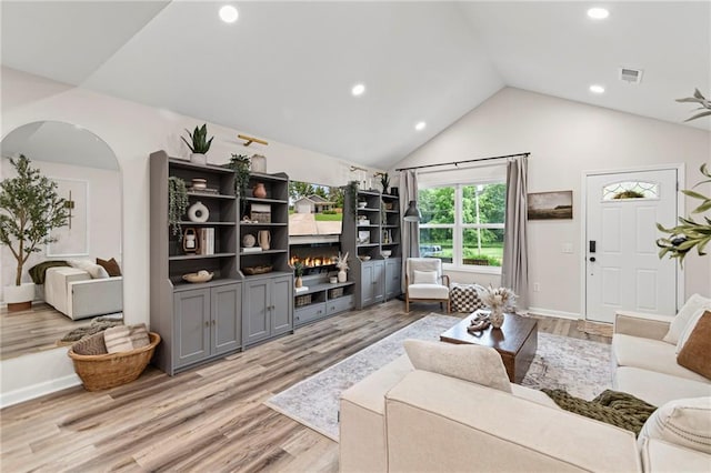 521 E Bird St, Hamilton, MO 64644 - living area with a lit fireplace, light wood-style floors, recessed lighting, arched walkways, and high vaulted ceiling