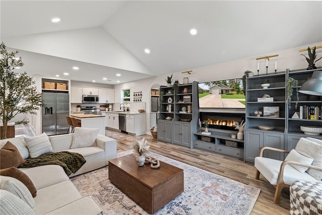 521 E Bird St, Hamilton, MO 64644 - living room with a lit fireplace, light wood-style floors, high vaulted ceiling, and recessed lighting