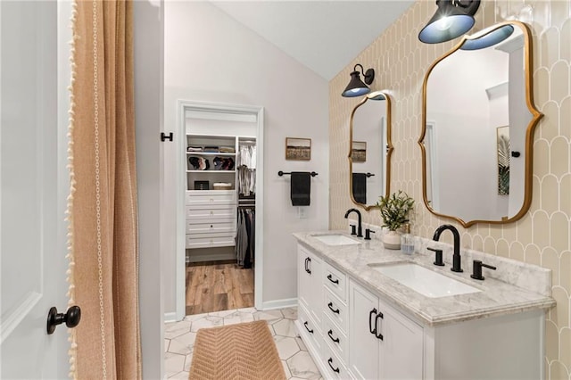 521 E Bird St, Hamilton, MO 64644 - bathroom featuring vaulted ceiling, double vanity, a walk in closet, and wallpapered walls
