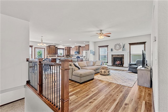 1658 Davis Cir, Eudora, KS 66025 - living room featuring healthy amount of natural light, ceiling fan, light wood-type flooring, and a warm lit fireplace