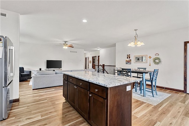 1658 Davis Cir, Eudora, KS 66025 - kitchen with dark brown cabinetry, light wood-style flooring, a ceiling fan, a chandelier, and freestanding refrigerator