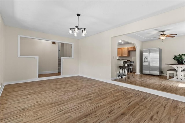 1004 SW Twilight Ln, Blue Springs, MO 64015 - unfurnished living room featuring wood finished floors, a ceiling fan, a chandelier, and arched walkways