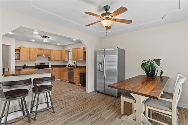 1004 SW Twilight Ln, Blue Springs, MO 64015 - kitchen with appliances with stainless steel finishes, under cabinet range hood, light wood-style flooring, a kitchen bar, and open shelves