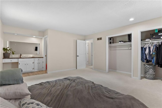 1004 SW Twilight Ln, Blue Springs, MO 64015 - bedroom featuring two closets, light carpet, ensuite bathroom, a textured ceiling, and recessed lighting