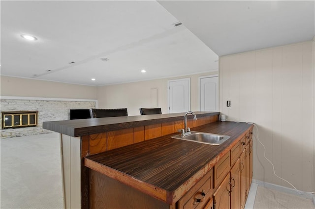 1004 SW Twilight Ln, Blue Springs, MO 64015 - kitchen featuring dark countertops, light colored carpet, recessed lighting, brown cabinetry, and a fireplace