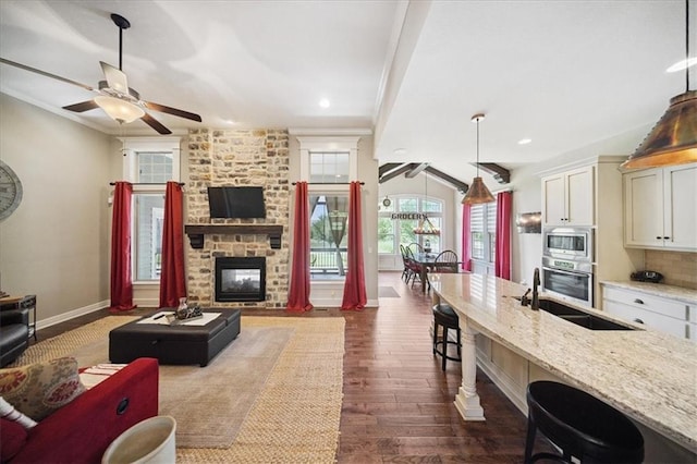 9158 W 178th Ter, Overland Park, KS 66013 - living area with ceiling fan, dark wood finished floors, a stone fireplace, crown molding, and recessed lighting