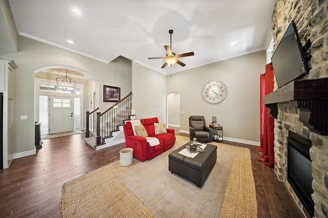 9158 W 178th Ter, Overland Park, KS 66013 - living room featuring arched walkways, a stone fireplace, stairway, crown molding, and a ceiling fan