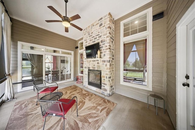 9158 W 178th Ter, Overland Park, KS 66013 - living room featuring ceiling fan, wood walls, plenty of natural light, and a stone fireplace