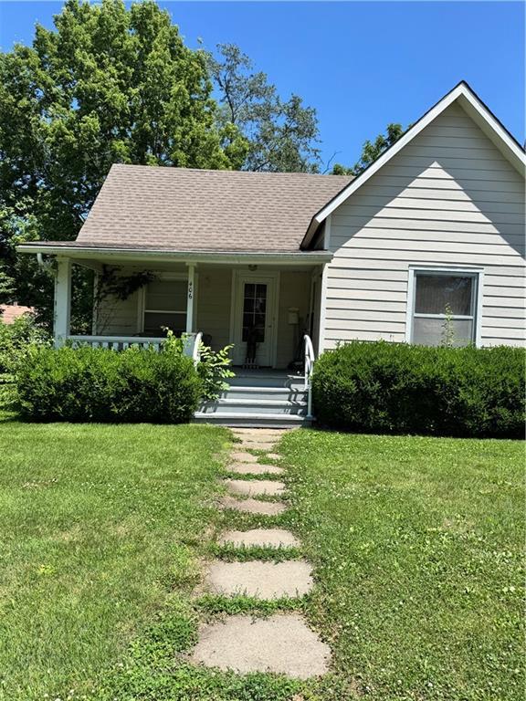 406 S 2nd St, Odessa, MO 64076 - view of front facade featuring a porch, a front lawn, and a shingled roof