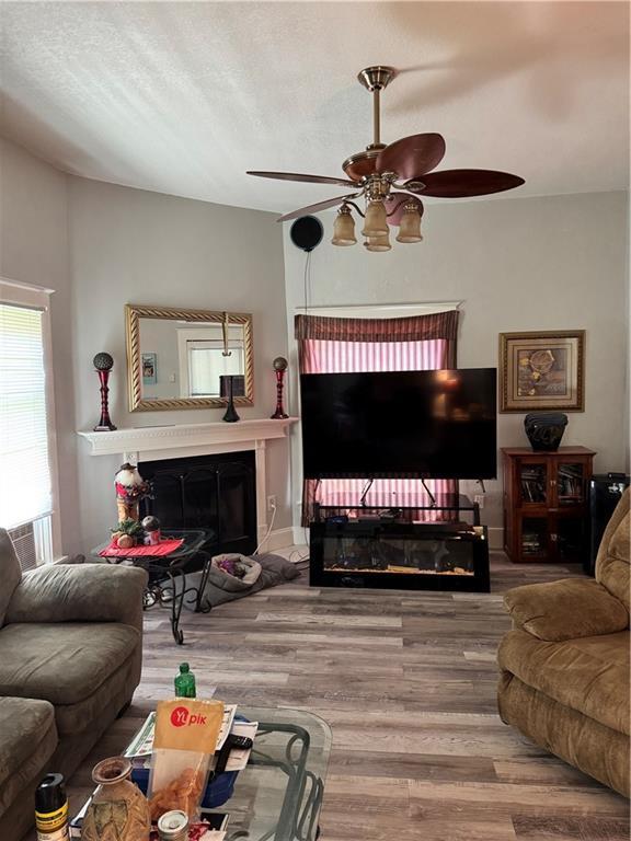406 S 2nd St, Odessa, MO 64076 - living area with a glass covered fireplace, a ceiling fan, and wood finished floors