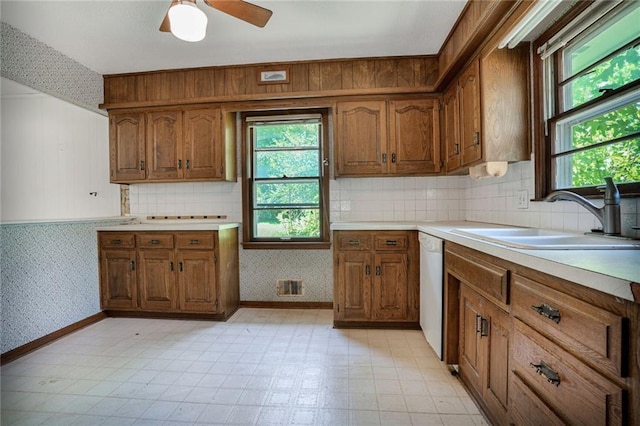 619 E 109th Ter, Kansas City, MO 64131 - kitchen with wallpapered walls, brown cabinetry, plenty of natural light, and white dishwasher
