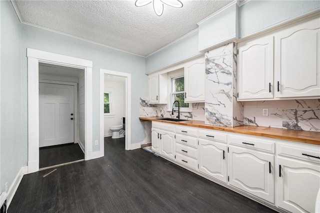 3344 Chestnut Ave, Kansas City, MO 64128 - kitchen featuring butcher block counters, tasteful backsplash, dark wood-style floors, white cabinetry, and a textured ceiling